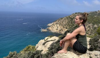 Frau sitzt auf einem Felsen und blickt auf auf das Meer rund um Mallorca
