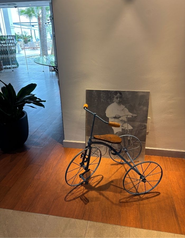 Altes Dreirad im Hotelfoyer mit Schwarz-Weiß-Foto eines Jungen im Hintergrund